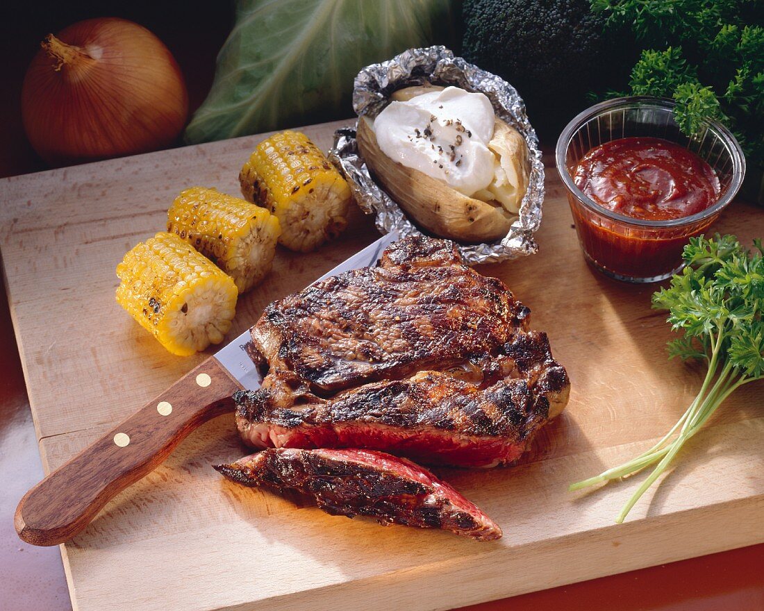 Partially Sliced Rib Eye Steak with Corn on the Cob