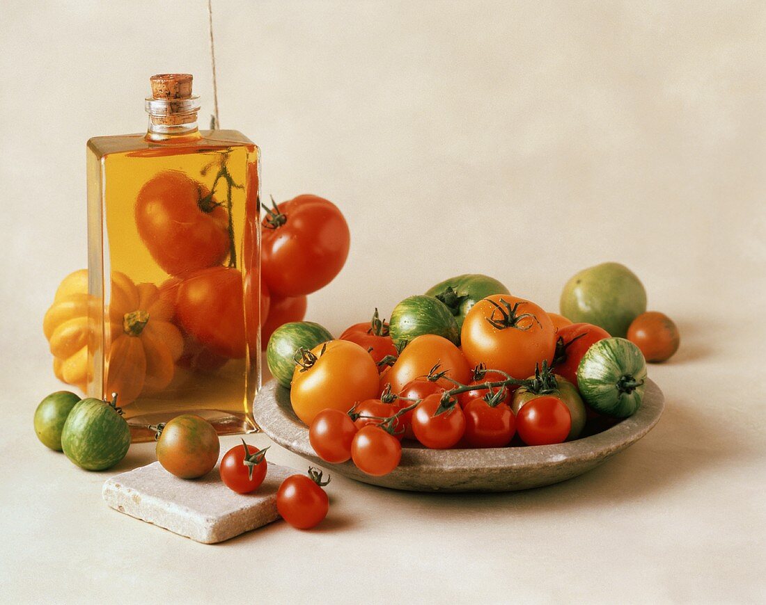 Verschieden rote, gelbe, grüne Tomaten und eine Flasche Öl