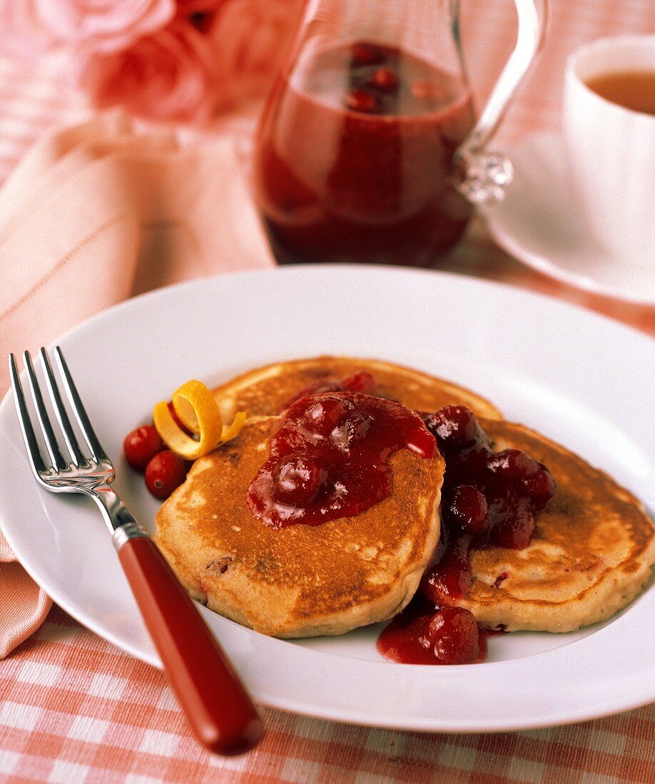 Pancakes mit Cranberrysauce auf weißem Teller mit Gabel