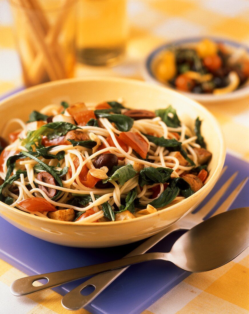 A Bowl of Spaghetti with Spinach Tomatoes Olives and Potatoes