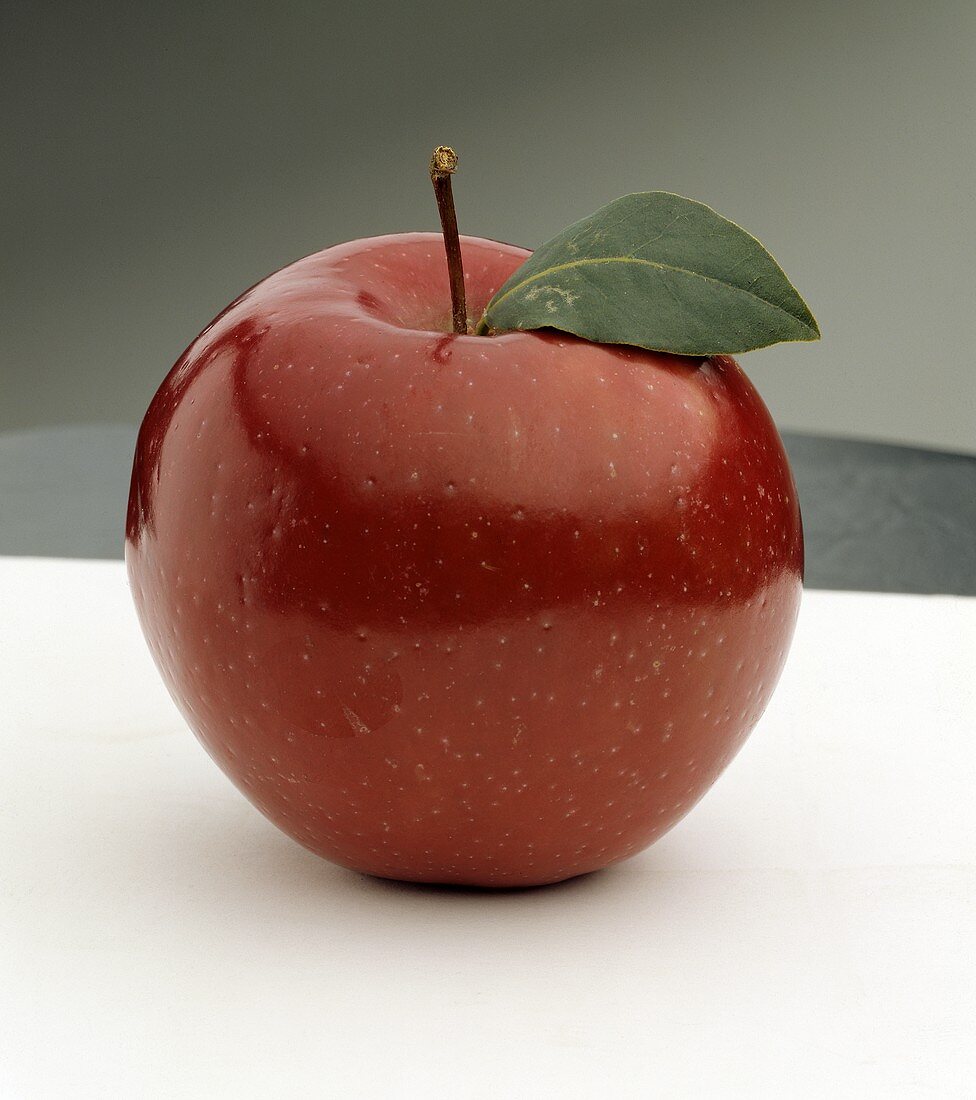 Ein polierter roter Apfel mit Stiel und Blatt