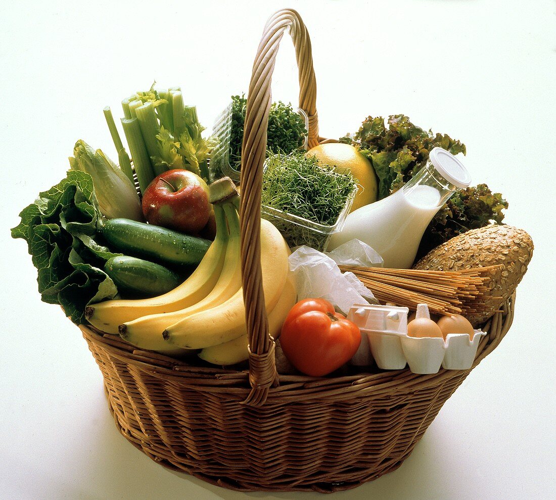 Korb gefüllt mit frischem Gemüse, Früchten, Milch & Brot