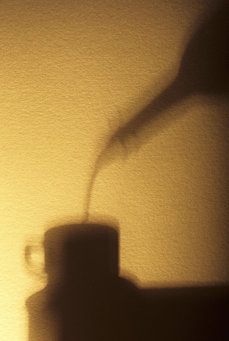 Flüssigkeit aus Flasche in Kaffeetasse gießen (Schattenbild)