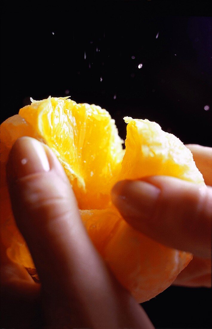 Hände teilen eine geschälte Orange