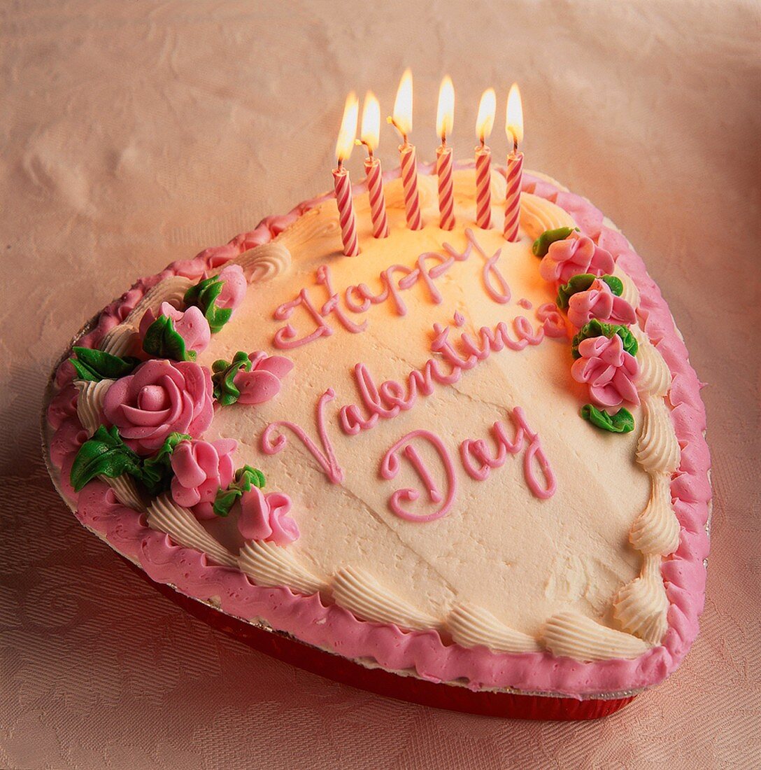 Herzförmige Torte zum Valentinstag mit brennenden Kerzen