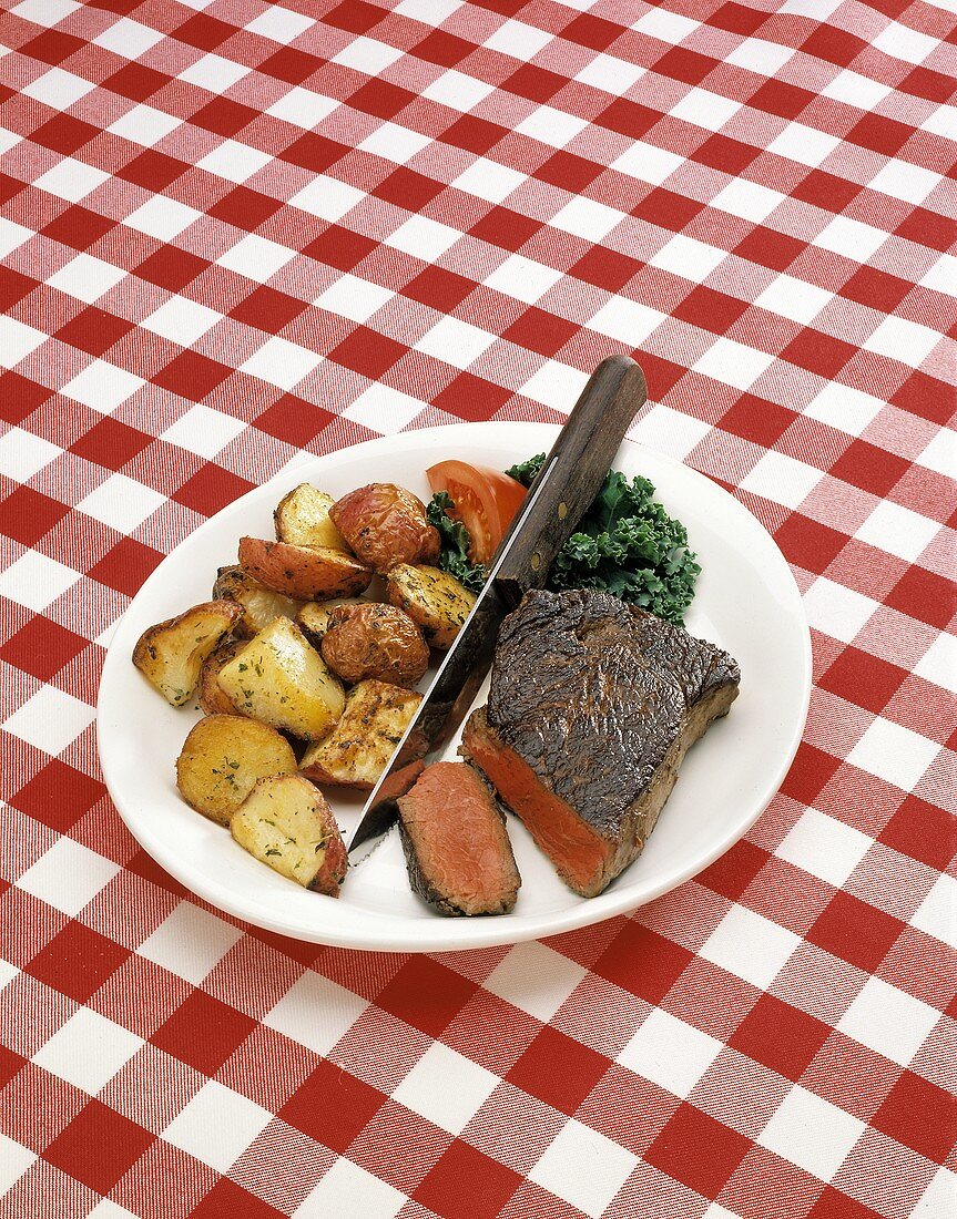 Rindersteak mit Bratkartoffeln auf weißem Teller