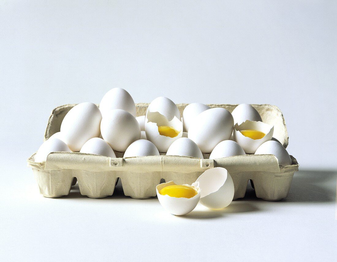 weiße Eier im Eierkarton, drei davon aufgeschlagen