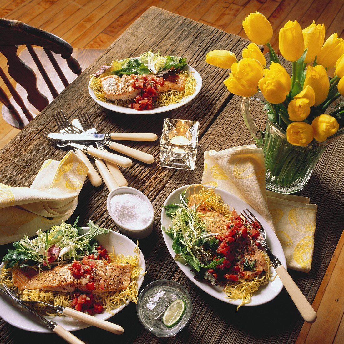 Lachsfilets mit Tomaten, Nudeln und Salat auf Holztisch