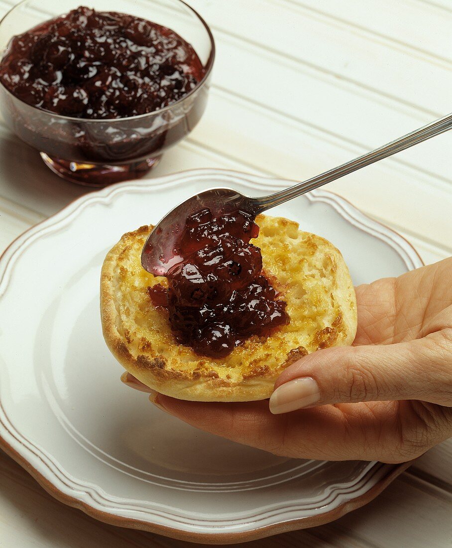 Spreading Apple Blueberry Jam on an English Muffin