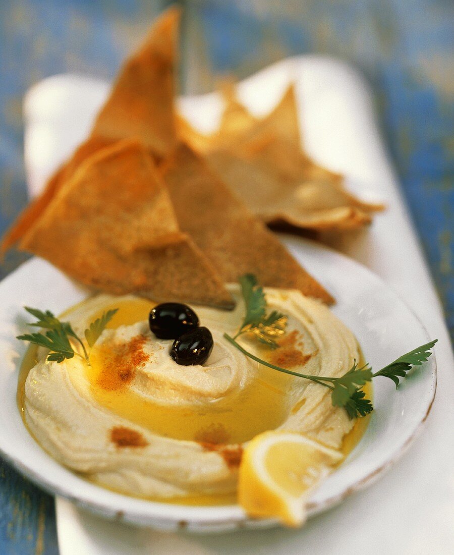 Hummus mit Olivenöl und Fladenbrot auf Teller
