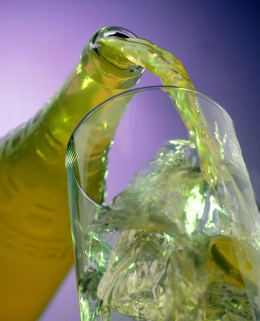 Limonade aus Flasche in Glas gießen