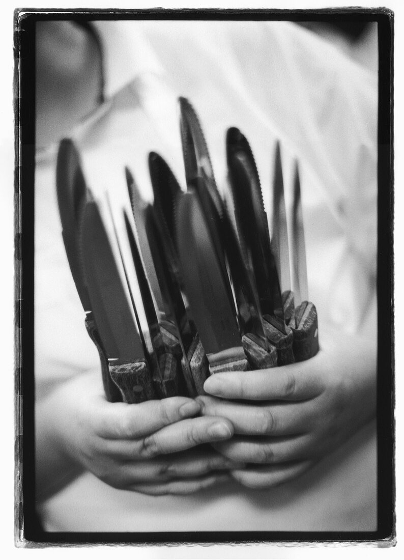 Hände halten mehrere Messer
