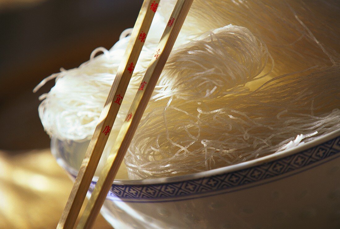 Asiatische Reisnudeln in Schale mit angelehnten Stäbchen