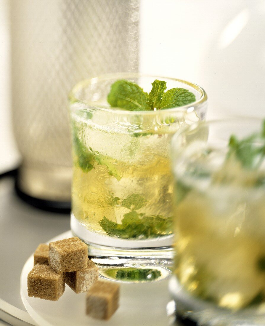 Mojito mit Rum und Minze; braune Zuckerwürfel