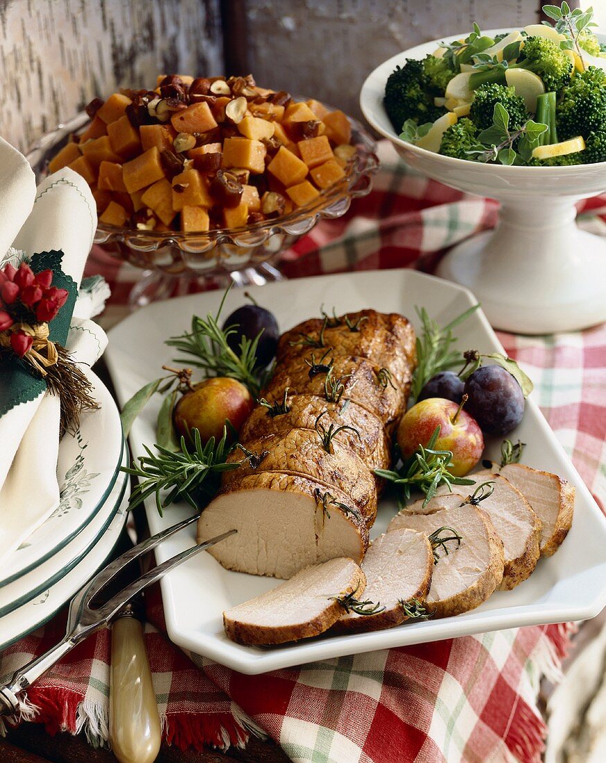 Schweinelendenbraten auf einer Platte mit Obst und Beilagen