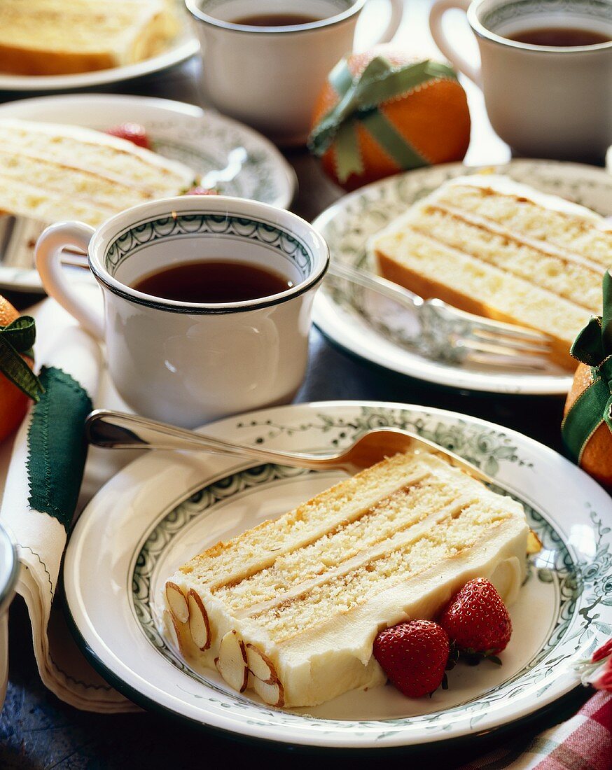 Slices of Layered Almond Cake on Plates with Cups of Coffee