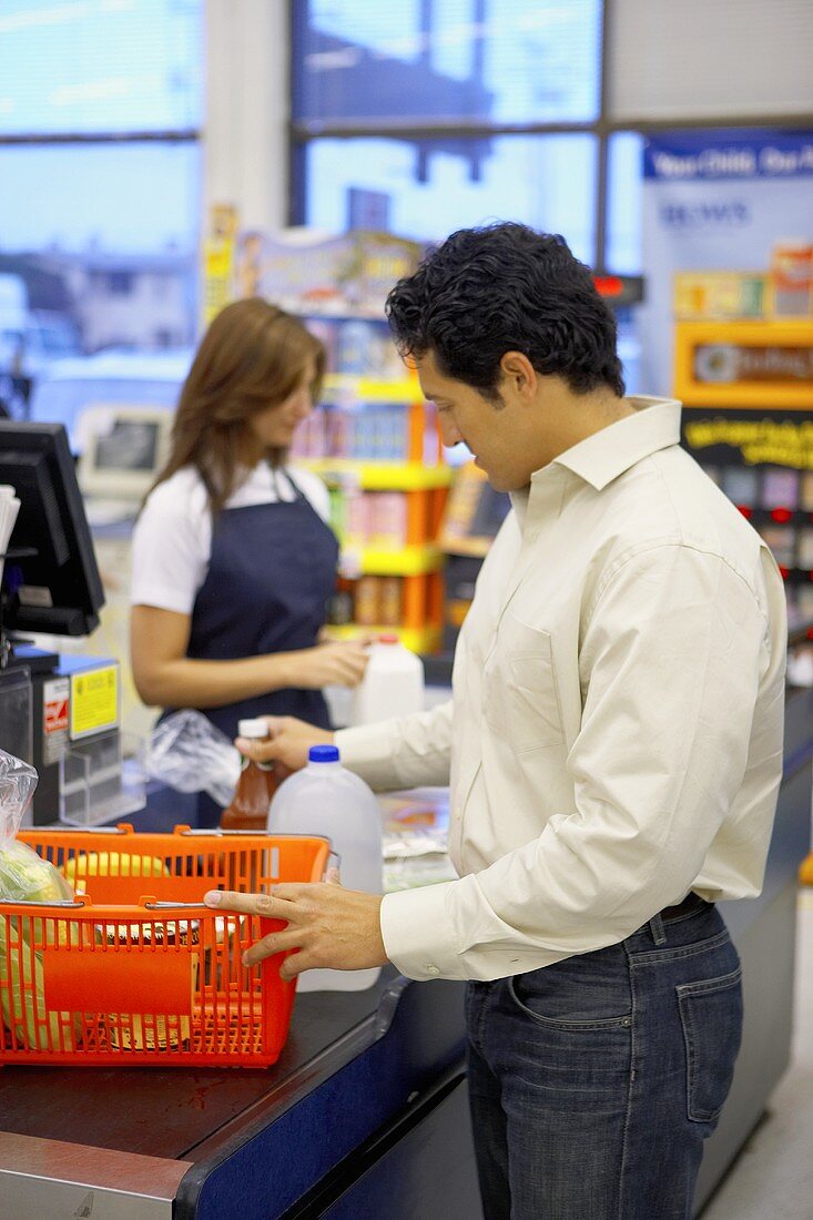 Man emptying basket at supermarket check-out