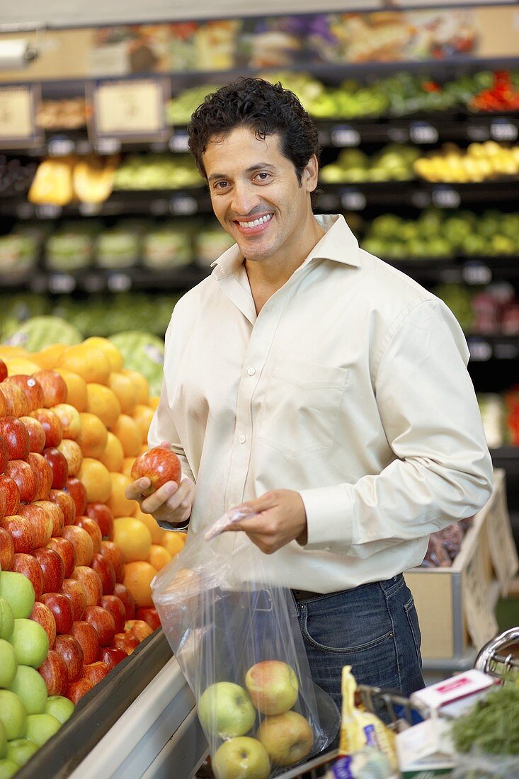 Mann füllt Äpfel in Plastiktüte am Obststand im Supermarkt