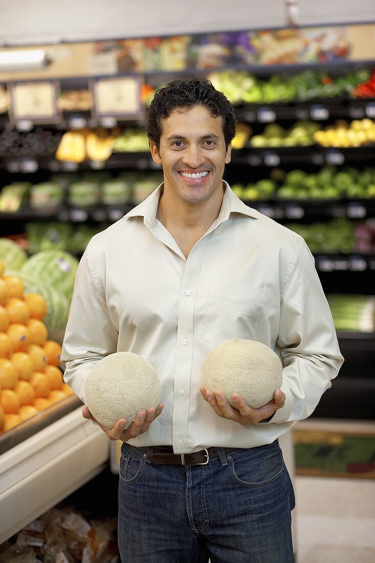 Man holding two melons in a supermarket