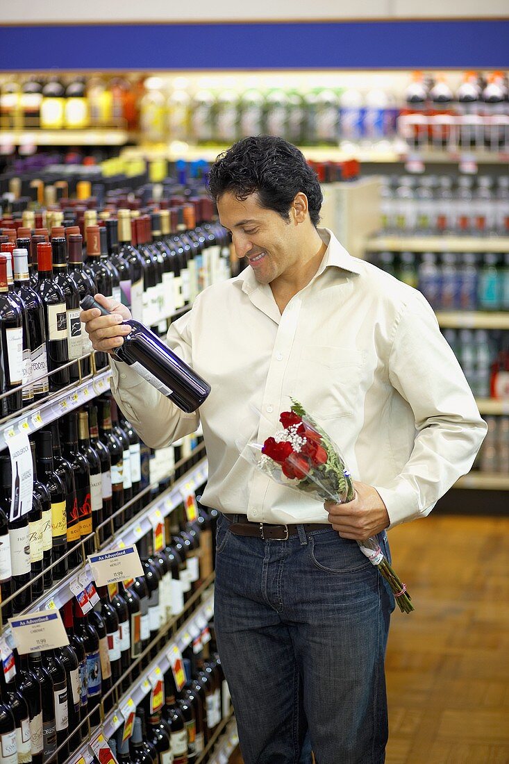 Man with bottle of wine and red roses in a supermarket