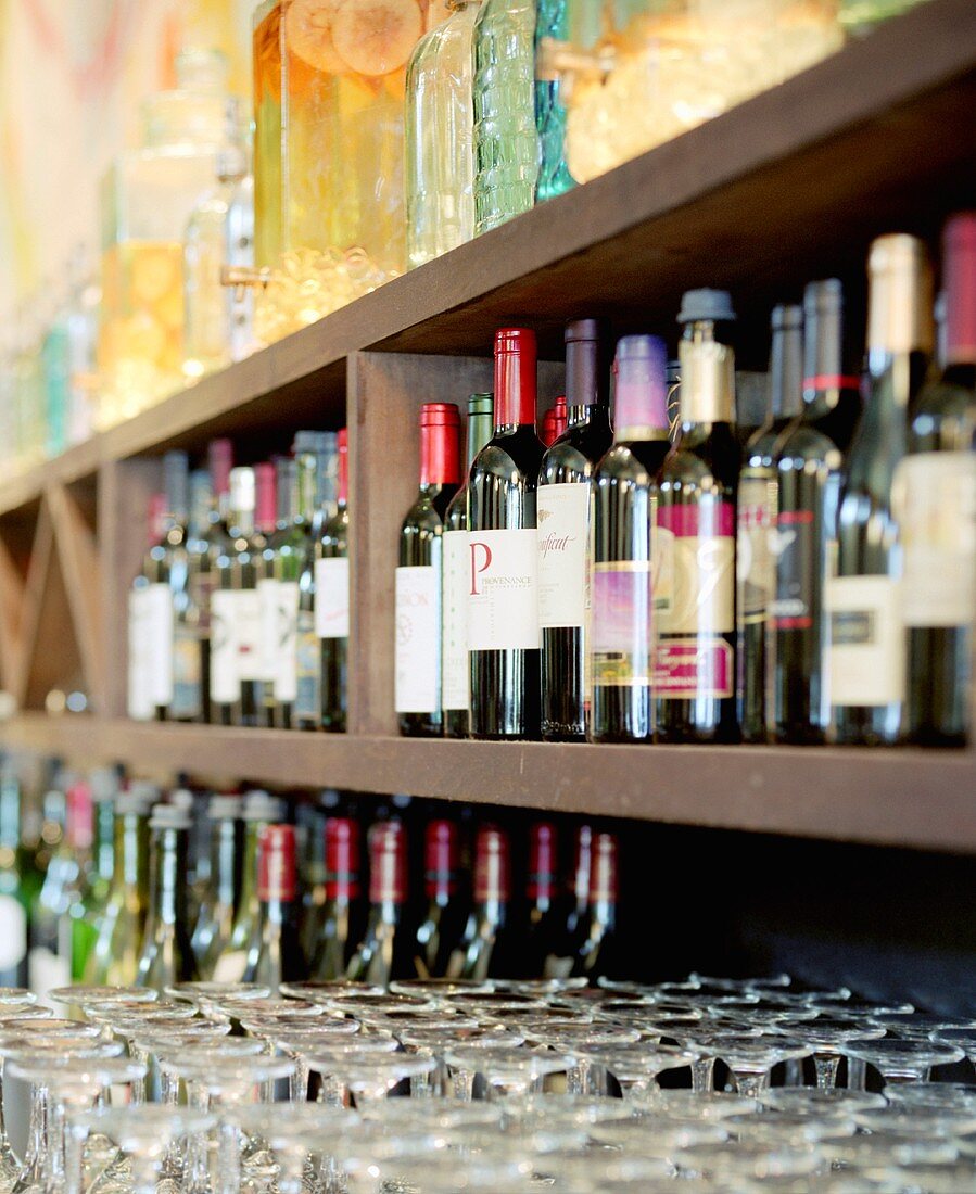Viele Weinflaschen in einer Bar, umgedrehte leere Weingläser