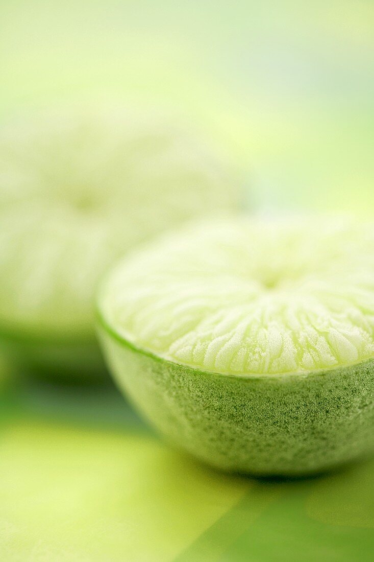 Two frozen lime halves on green background