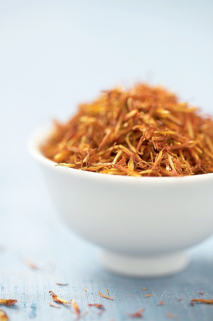 Dried safflower petals in white bowl