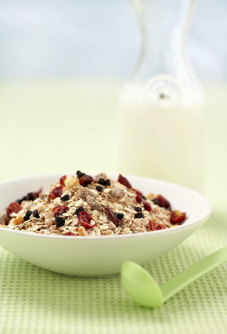 Muesli with dried fruit in front of bottle of milk