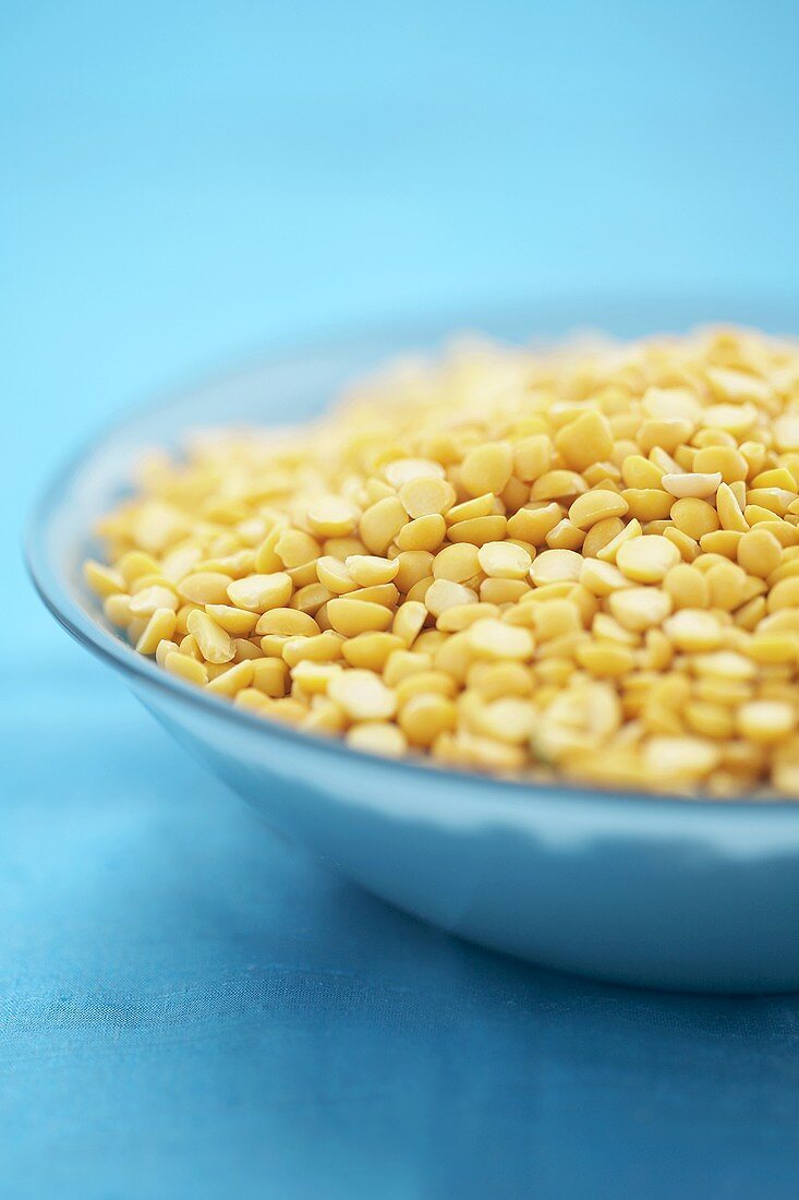 Yellow split peas in blue bowl on blue background