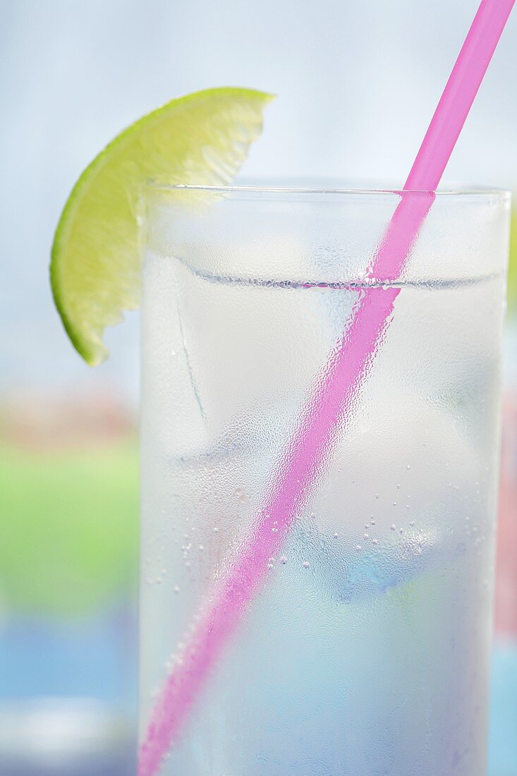 Glas Tonic Water mit Eiswürfeln, Limette und Strohhalm