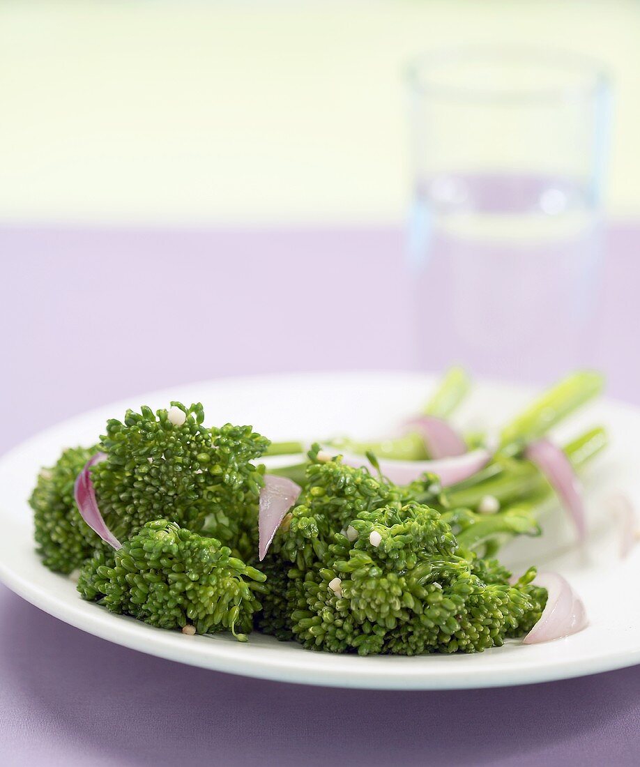 Broccolini mit roten Zwiebeln auf weißem Teller