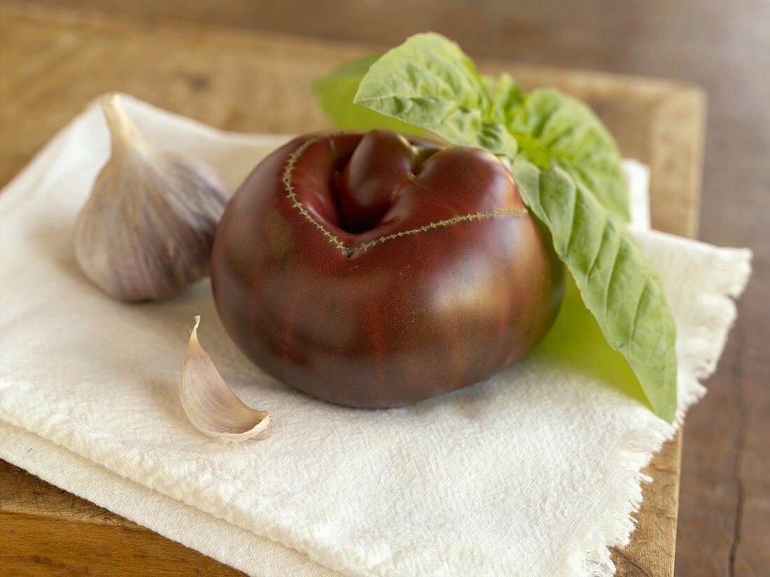 Frischer Knoblauch, Tomate und Basilikum auf Geschirrtuch