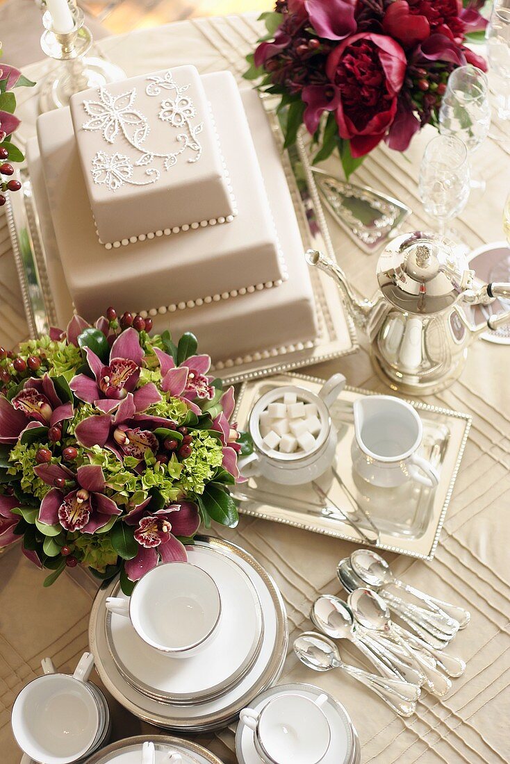 Three-tiered white wedding cake, flowers and tea set