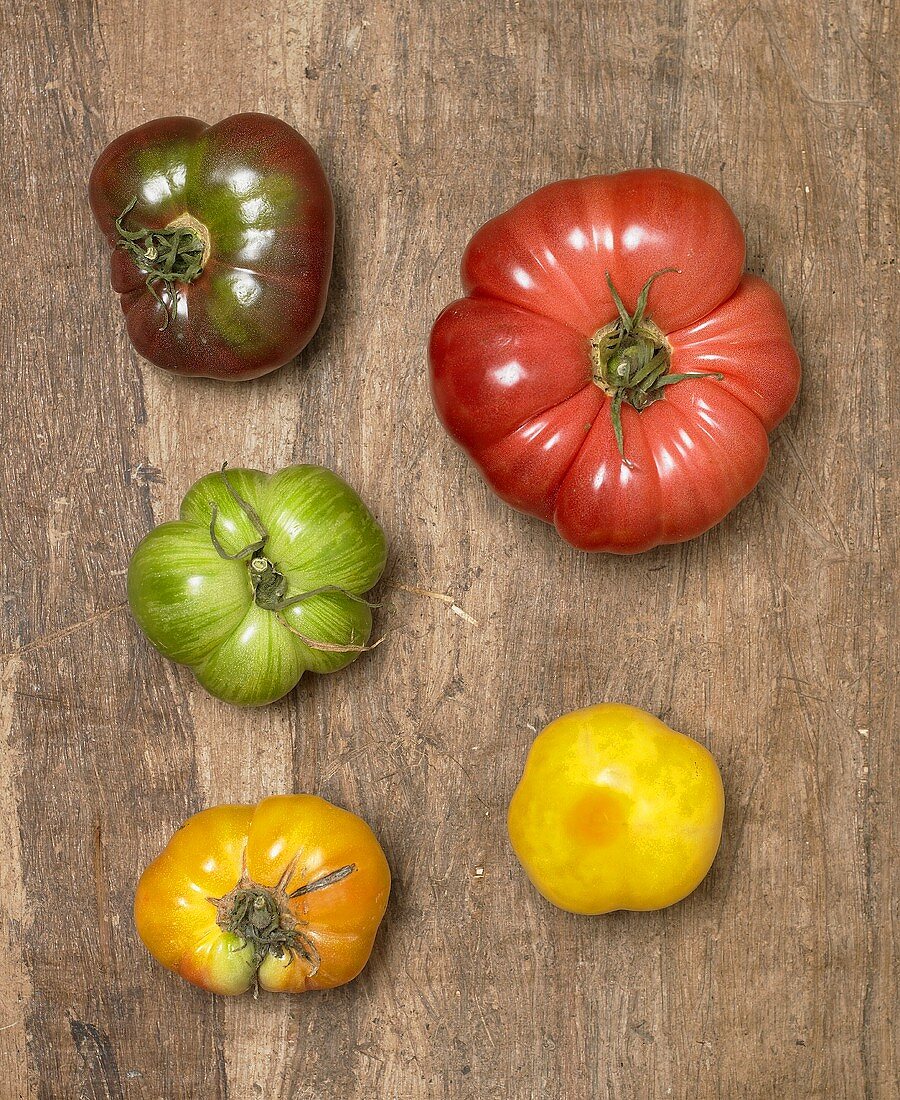 Fünf Heirloom Tomaten auf Holzuntergrund (Draufsicht)