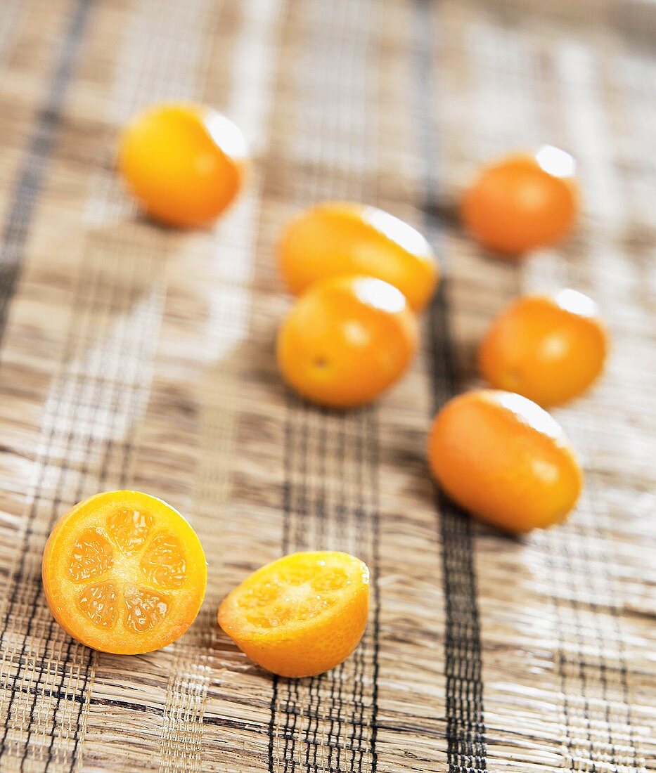 Mehrere Kumquats, eine davon halbiert