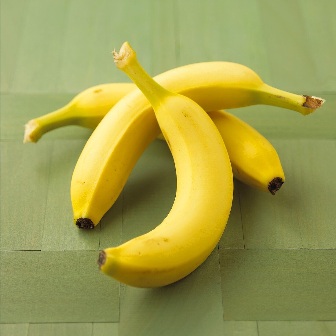 Three bananas on a green background