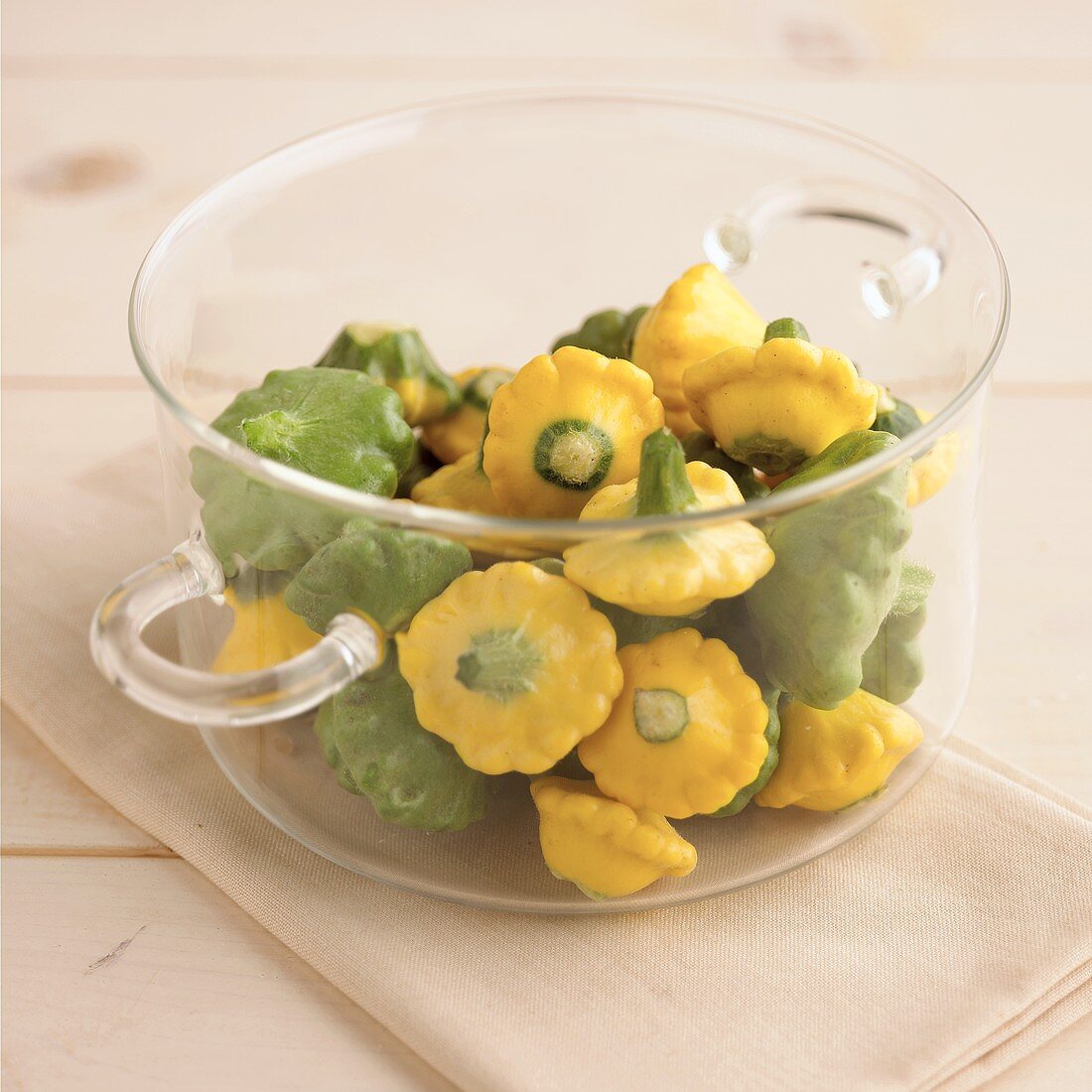 Green and yellow baby patty pan squashes in glass bowl