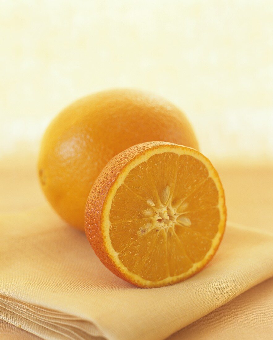 Orange half in front of whole orange