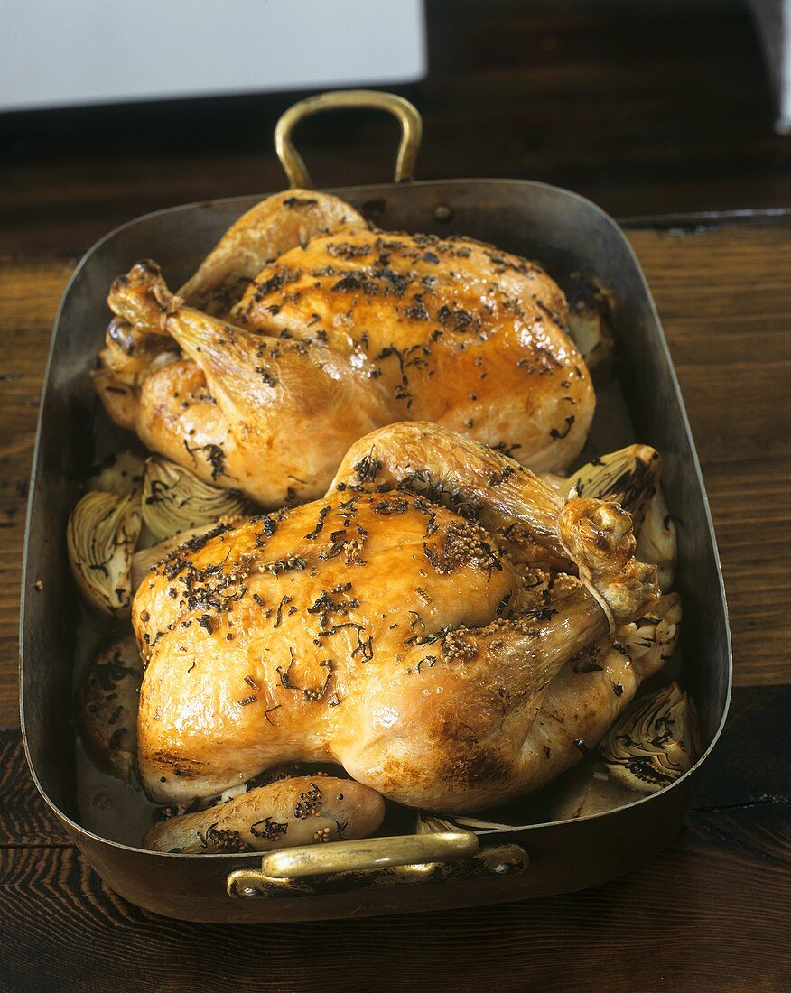 Two roast chickens in a roasting dish