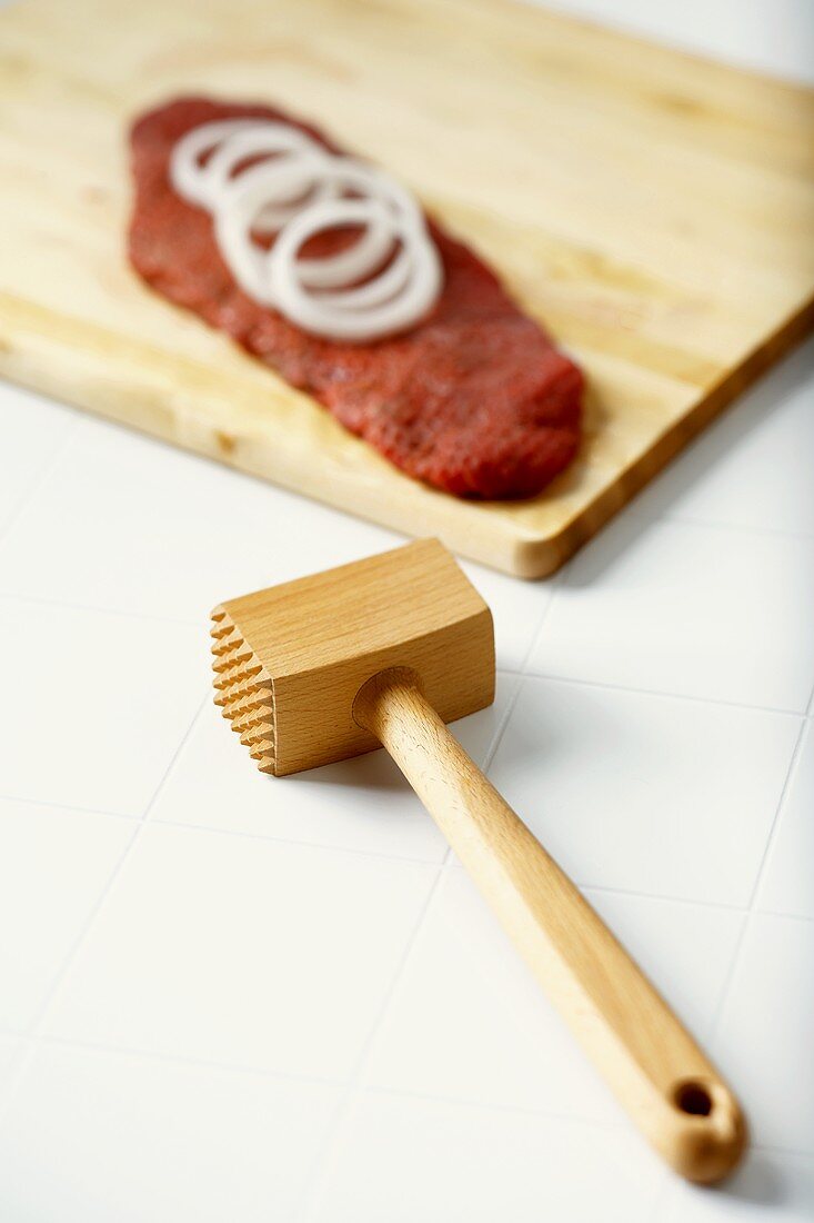 Wooden Meat Tenderizer, Pounded Meat with Onion Slices on Cutting Board