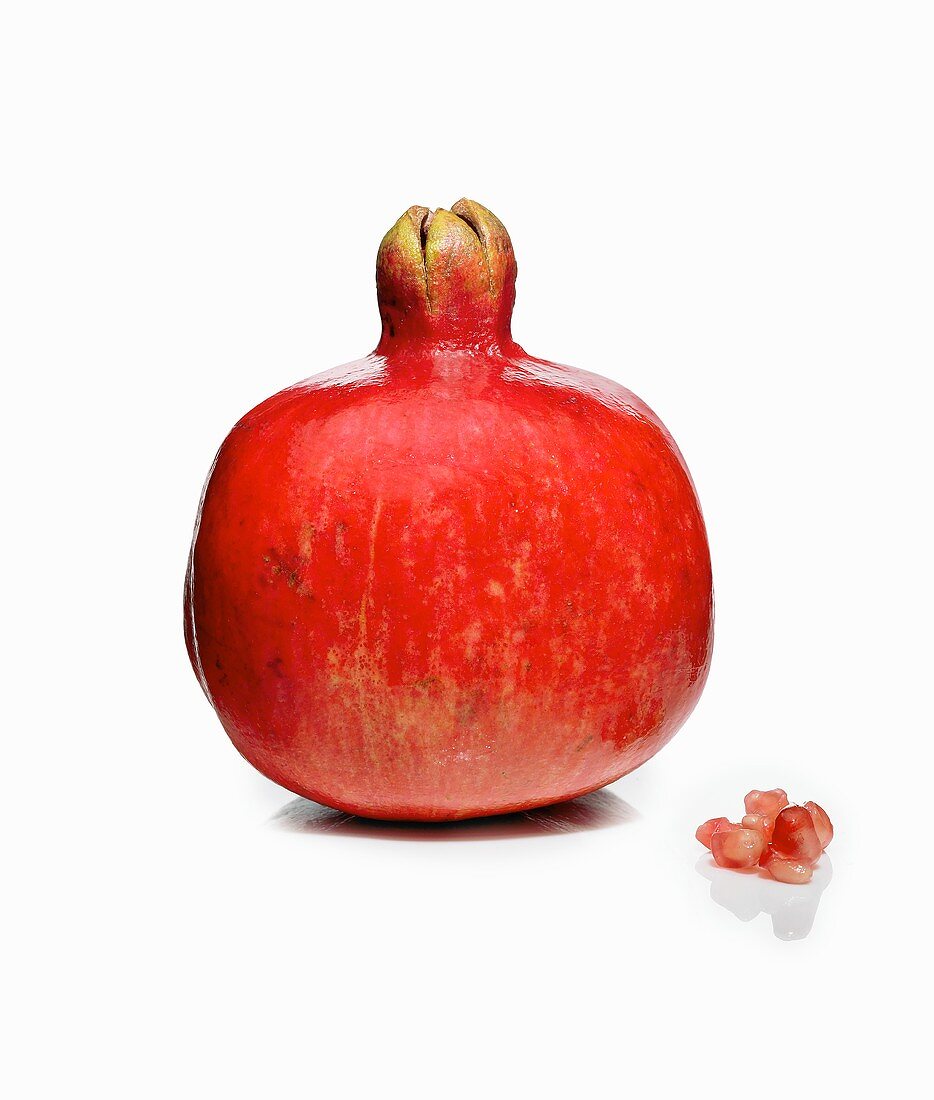 Whole Pomegranate with Small Piece of Pomegranate on a White Background