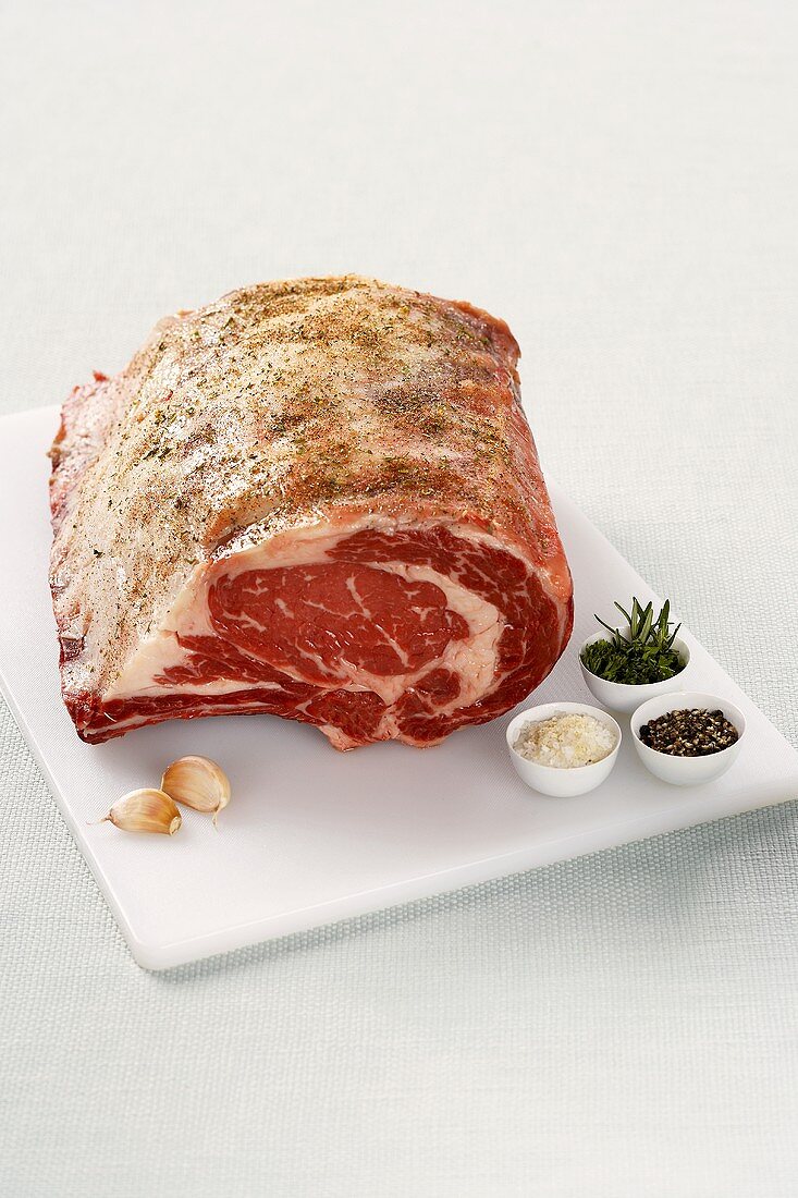 Rib Roast on a Cutting Board with Garlic and Herbs, White Background