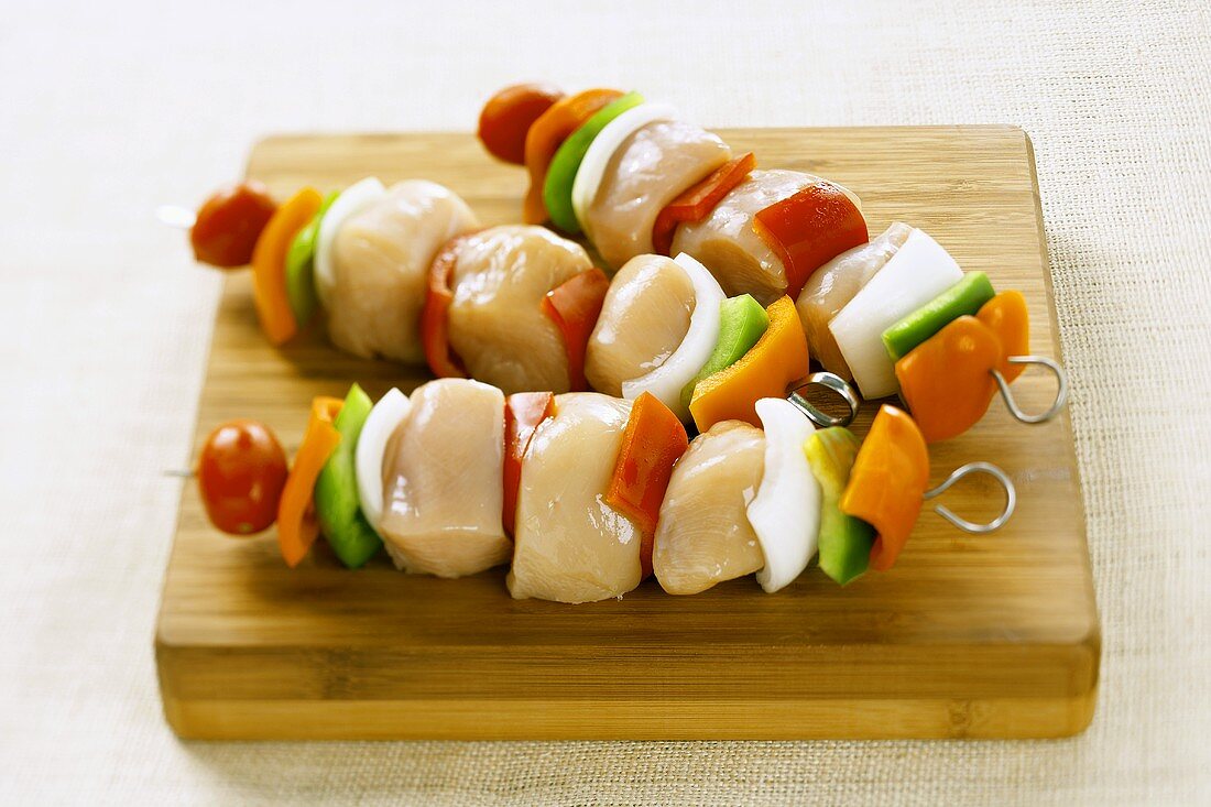 Uncooked Chicken and Vegetable Kabobs on a Cutting Board
