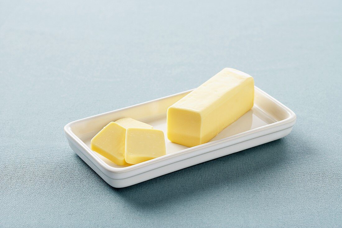 Stück Butter in weisser Butterdose
