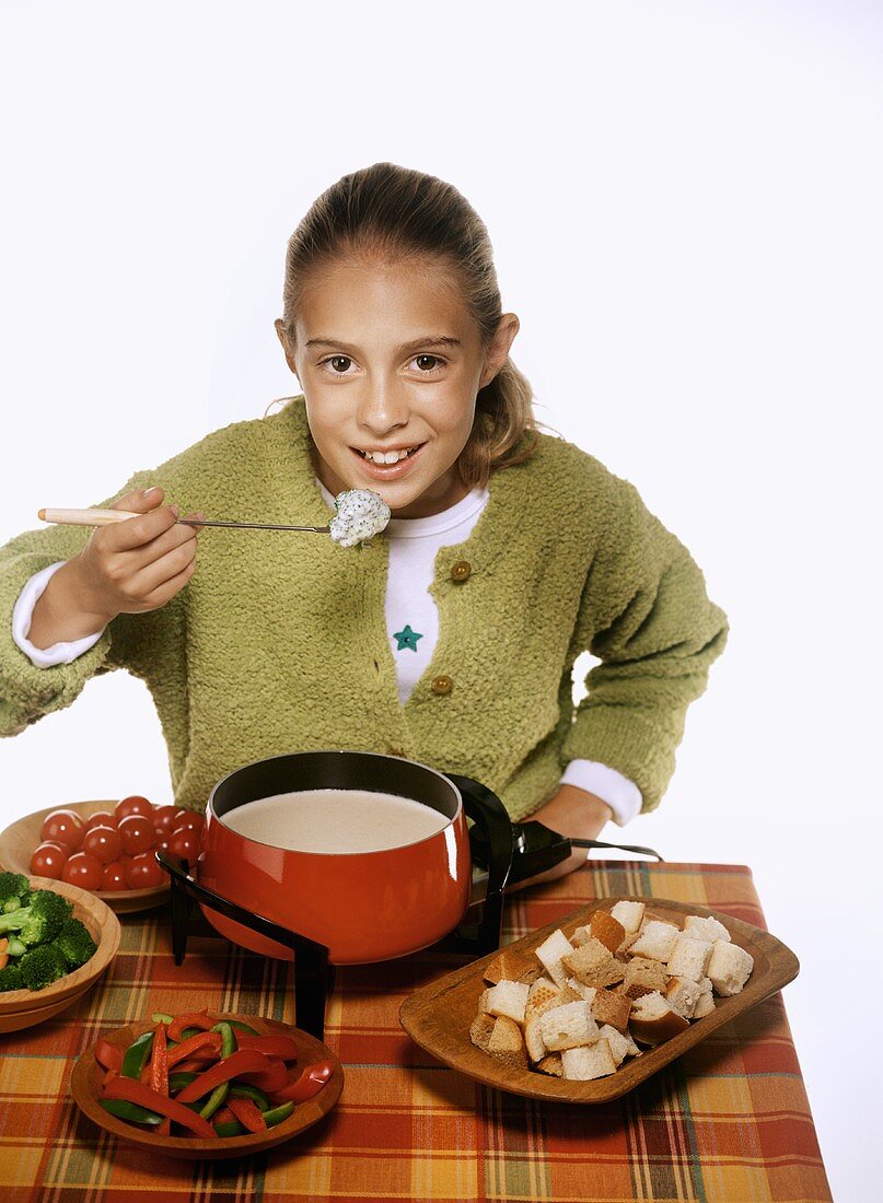 Girl About to Eat Bread Dipped in Cheese Fondue, Fondue Pot with Cheese Fondue, Bread and Vegetables