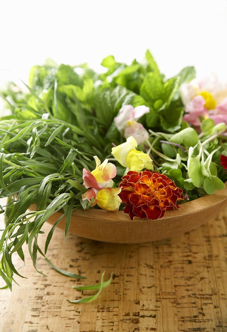 Frische Kräuter und Blüten in Holzschale