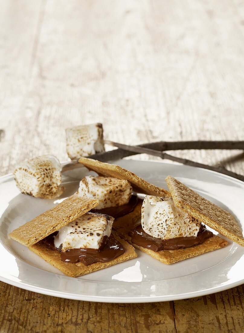 Three S'mores on a White Plate, Marshmallows on Roasting Sticks