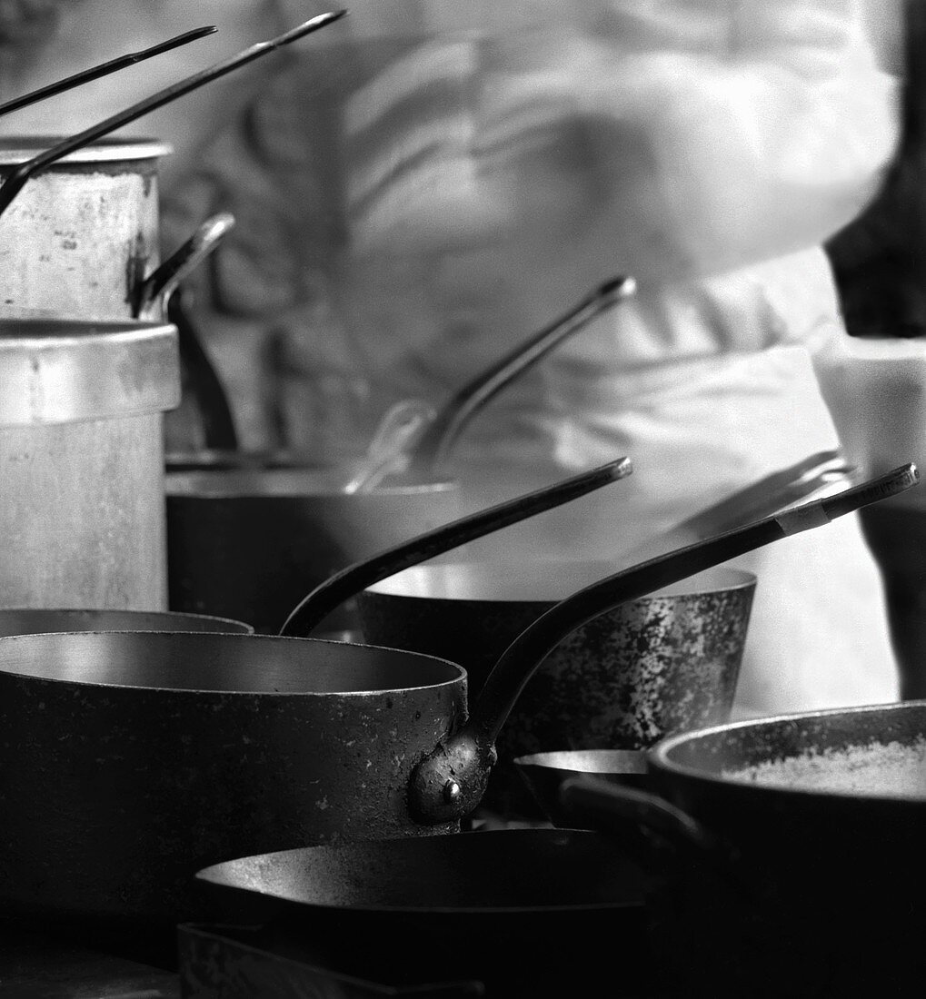 A Variety of Saucepans with Chef in Background