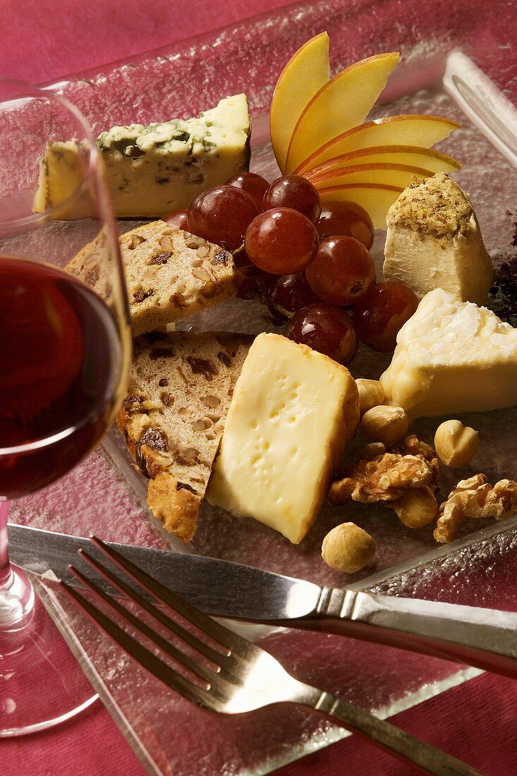 Käseplatte mit Früchten, Nüssen und Glas Rotwein