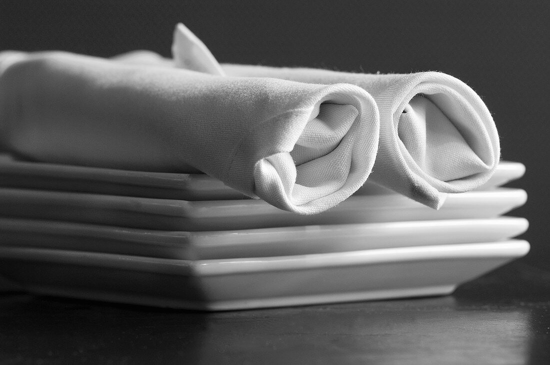 Rolled Napkins on a Stack of Square Plates